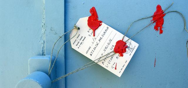Etiquette de scellé judiciaire apposée sur une porte bleue