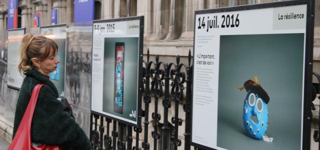 Personne regardant l'exposition "Face au terrorisme, une mémoire citoyenne" sur les grilles de l'Hôtel de ville