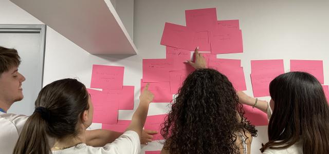 4 personnes en rélexion devant un mur de post-il lors d'un focus groupe