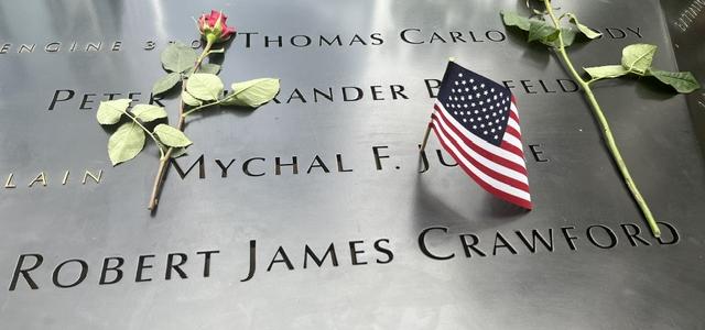Fleurs et drapeaux américains déposés sur le bord de l'un des bassins de à Ground Zero gravé de noms de victimes