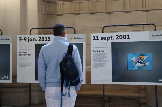 Un homme devant un panneau de l'exposition  photographique "Face au terrorisme, un patrimoine à inventer" lors des JEP 2026 à la Cour d'appel de Paris