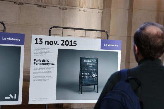 Un homme de dos face à un panneau de l'exposition photographique "Face au terrorisme, un patrimoine à inventer" lors des JEP 2026 à la Cour d'appel de Paris