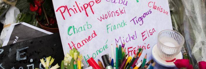 Feuille avec le nom des victimes de l'attentat de Charlie Hebdo, fleurs et bougies déposées dans un mémorial éphémère