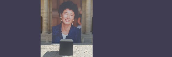 Portrait géant de Françoise Rudetzki devant une couronne de fleurs