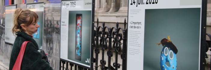 Personne regardant l'exposition "Face au terrorisme, une mémoire citoyenne" sur les grilles de l'Hôtel de ville