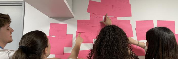 4 personnes en rélexion devant un mur de post-il lors d'un focus groupe