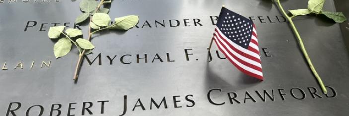 Fleurs et drapeaux américains déposés sur le bord de l'un des bassins de à Ground Zero gravé de noms de victimes